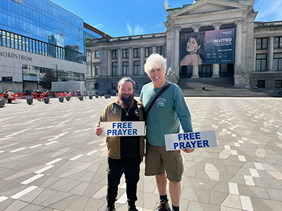 Anthony Bucci and Ralph Lavallee holding free prayer signs.