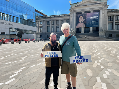 Gary Smith and Ralph Lavallee holding free prayer signs.