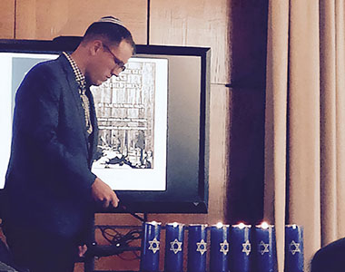 Ty Perry lights a candle at a Yom HaShoah commemoration.